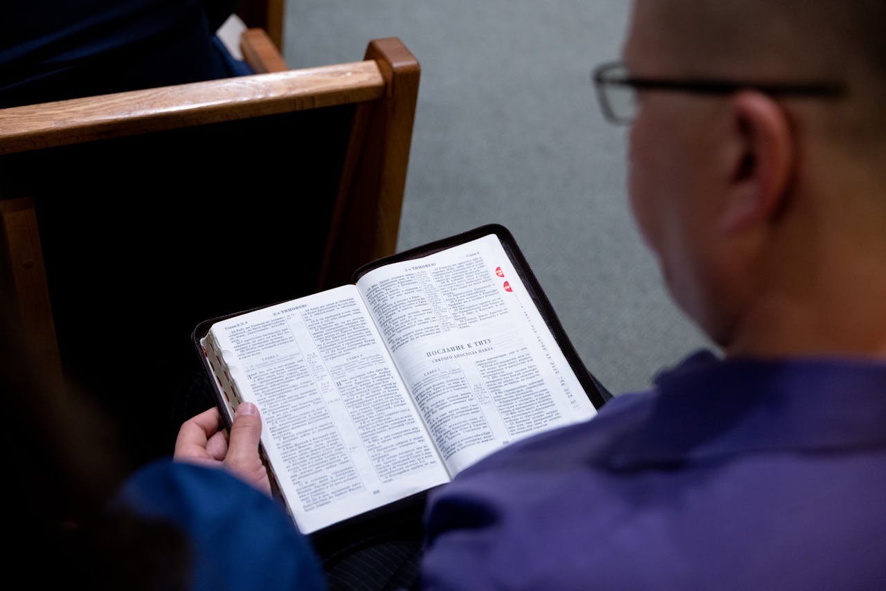 services-bg An individual studies a Bible while seated in a church. Focus on faith and reflection.